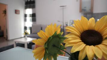 Ein Zimmer im modernen Stil, mit einem Glastisch und einer Vase mit Sonnenblumen.