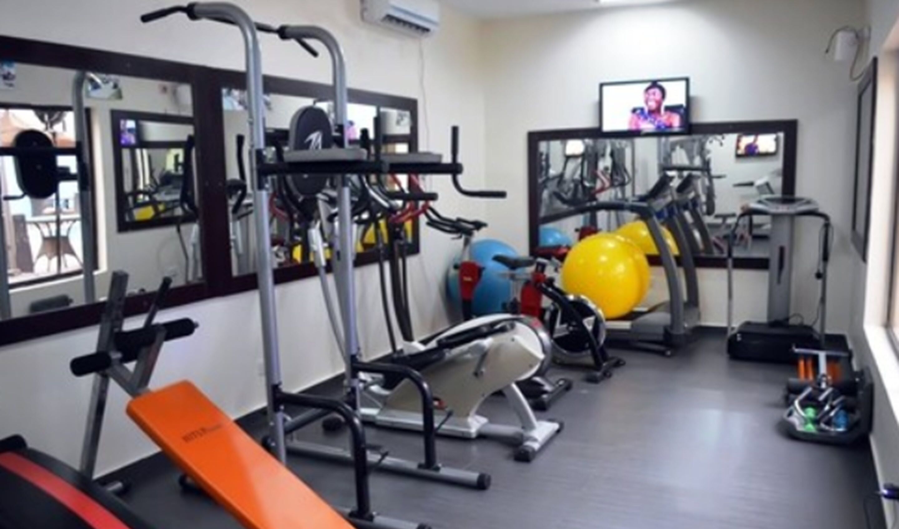 Une salle de sport équipée de matériel d’exercice, d’un banc et d’un écran de télévision.