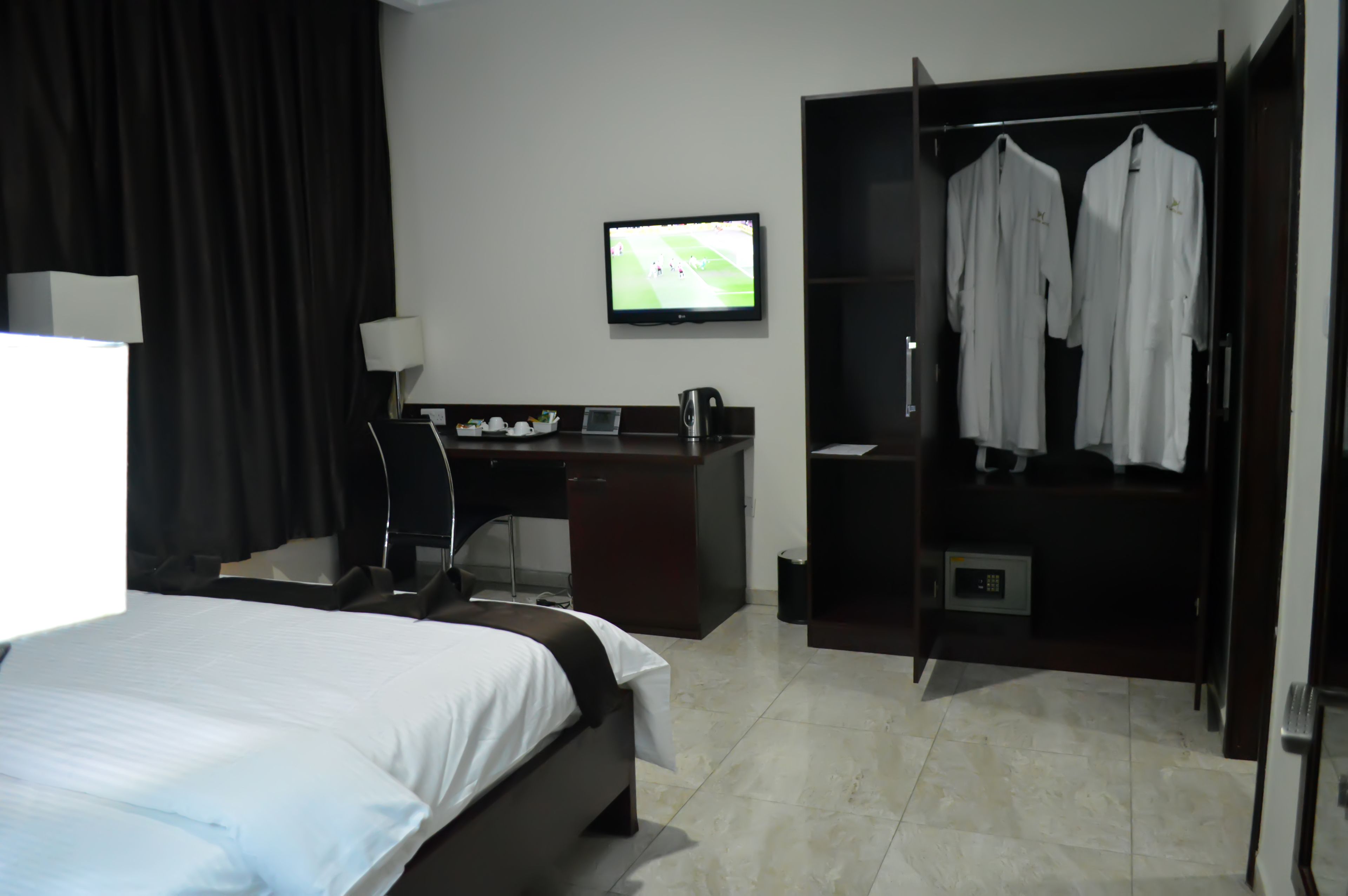 Una habitación de hotel con cama, escritorio, televisor y armario.