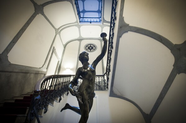 Un escalier orné d’une statue, d’une horloge et d’une lucarne.