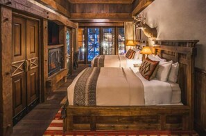 A rustic wooden room with a large bed, a fireplace, and a deer mounted on the wall. - Big Cypress Lodge (Memphis)