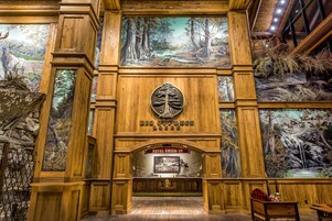 A hotel lobby with wooden paneling, a check-in desk, and large wildlife murals on the walls.