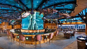 A spacious bar area with a central bar, seating around it, and a large aquarium with aquatic life. - Big Cypress Lodge (Memphis)