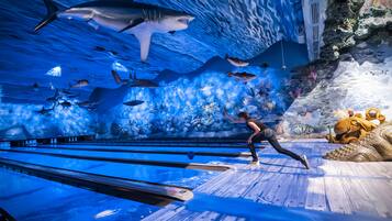 A bowling alley with a large aquarium wall displaying various marine life.