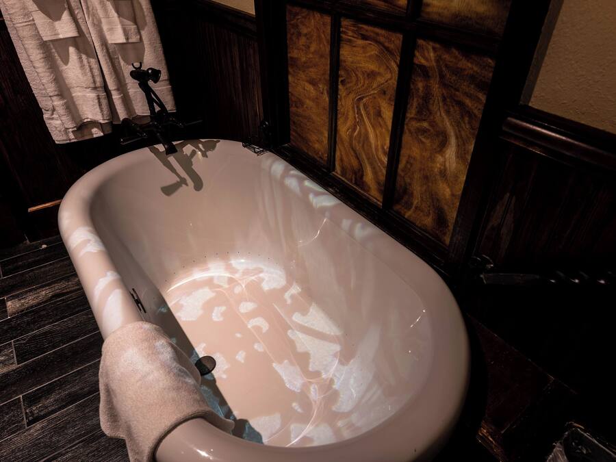 A bathtub with a wooden panel wall and a towel hanging on the side.