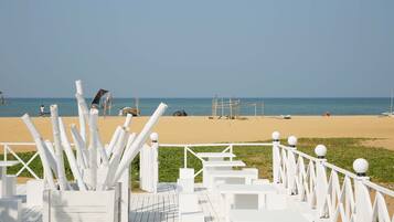 A beachside walkway with white railings and steps leading to the beach.