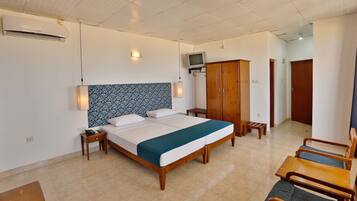 A hotel room with a bed, bedside tables, a wardrobe, a television, and a seating area.