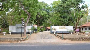 A sign for JAYASWATHI Holiday Resort with a paved entrance and surrounding greenery. - Jayasinghe Holiday Resort (Kataragama)