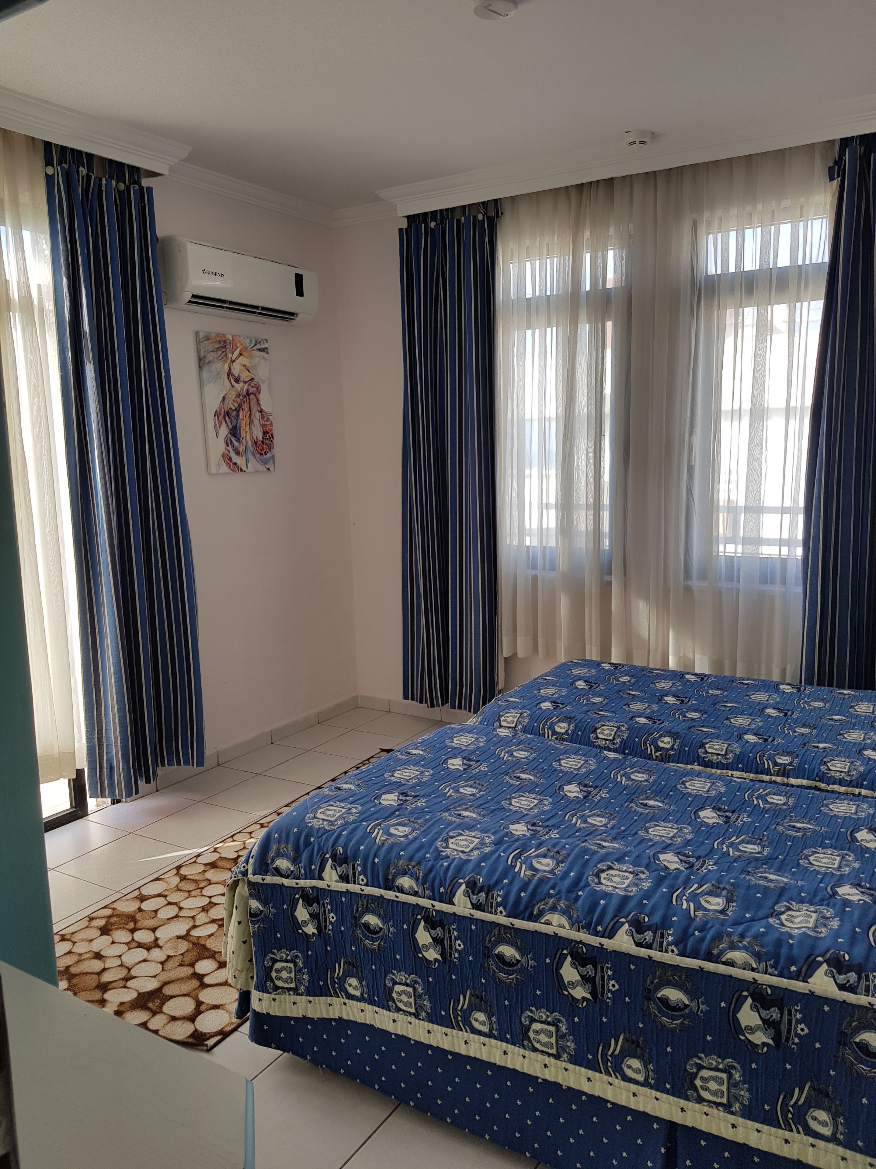 Un dormitorio con una cama grande, aire acondicionado y una alfombra estampada.