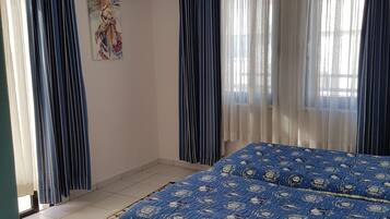 Un dormitorio con una cama grande, aire acondicionado y una alfombra estampada.