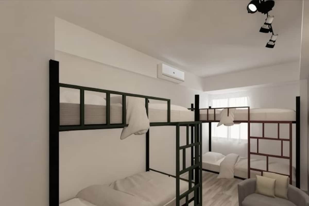 A bunk bed room with a desk and chair, a window, and a ceiling light fixture.