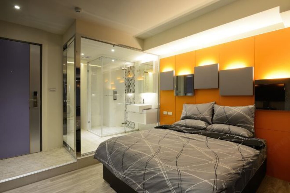 Une chambre moderne avec un grand lit, une douche en verre et un téléviseur fixé au mur.