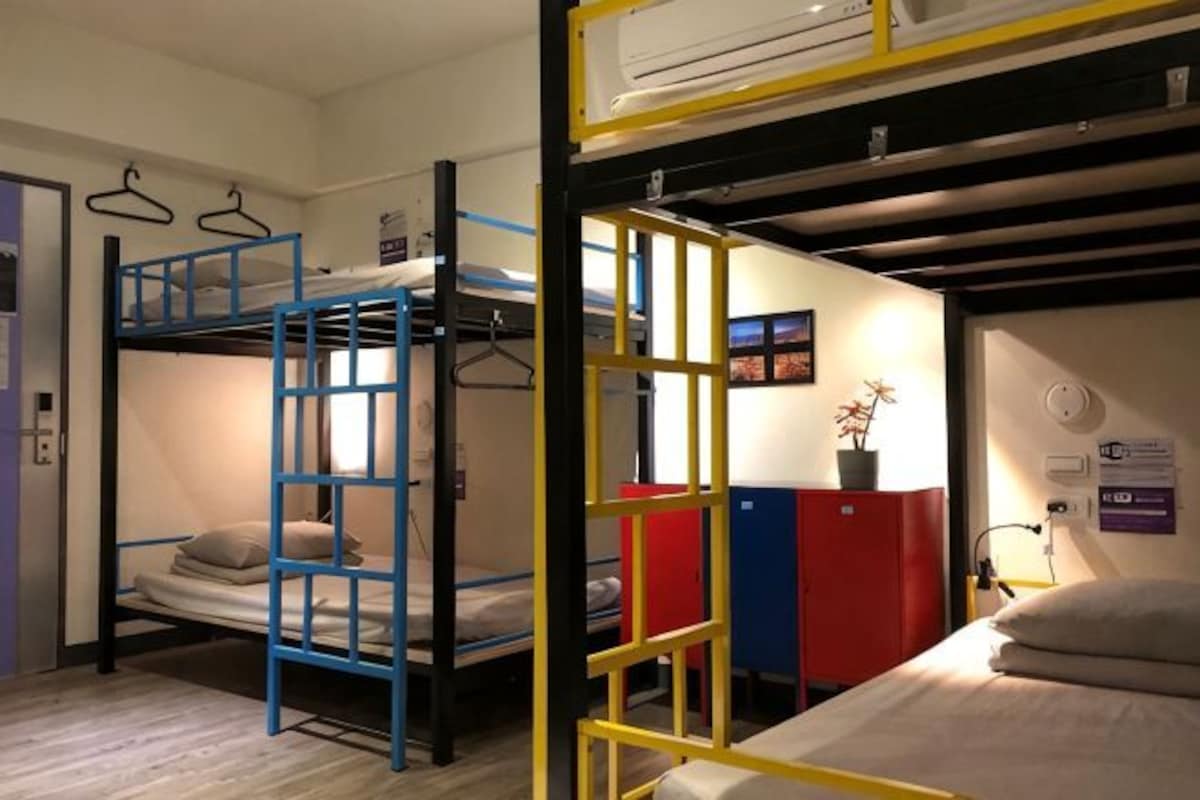 A bunk bed room with a ladder, a desk, and a chair.