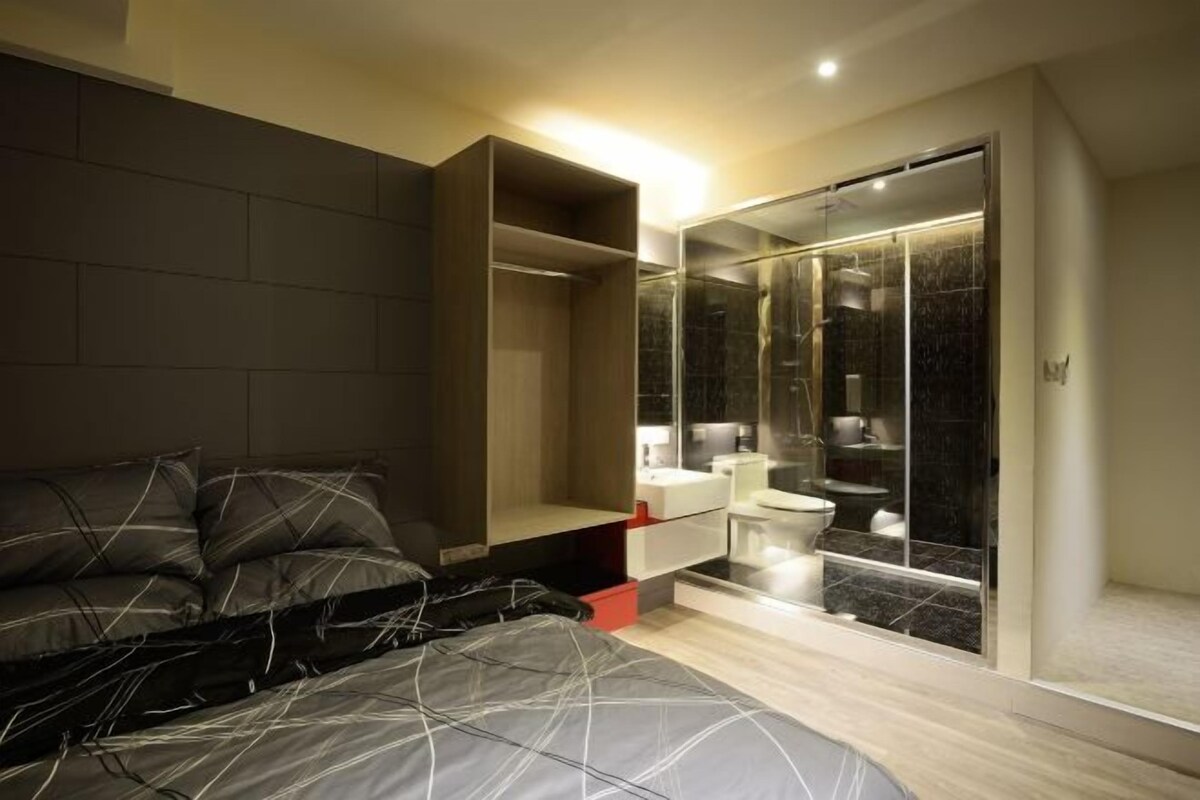 A modern bedroom with a large bed, built-in wardrobe, and a glass-enclosed shower area.