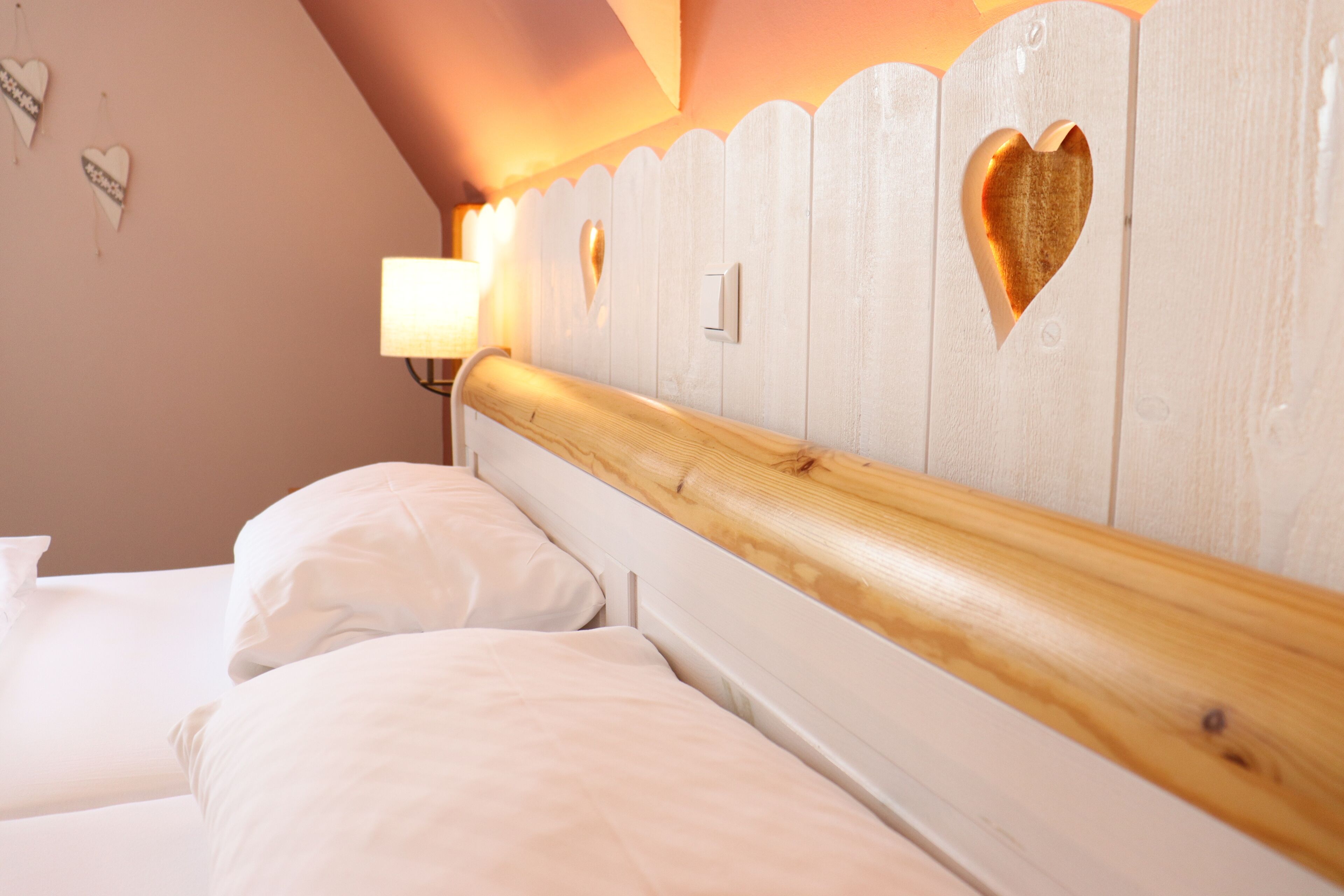 Un dormitorio con cabecera de madera, dos camas, una mesita de noche y una lámpara de pared.