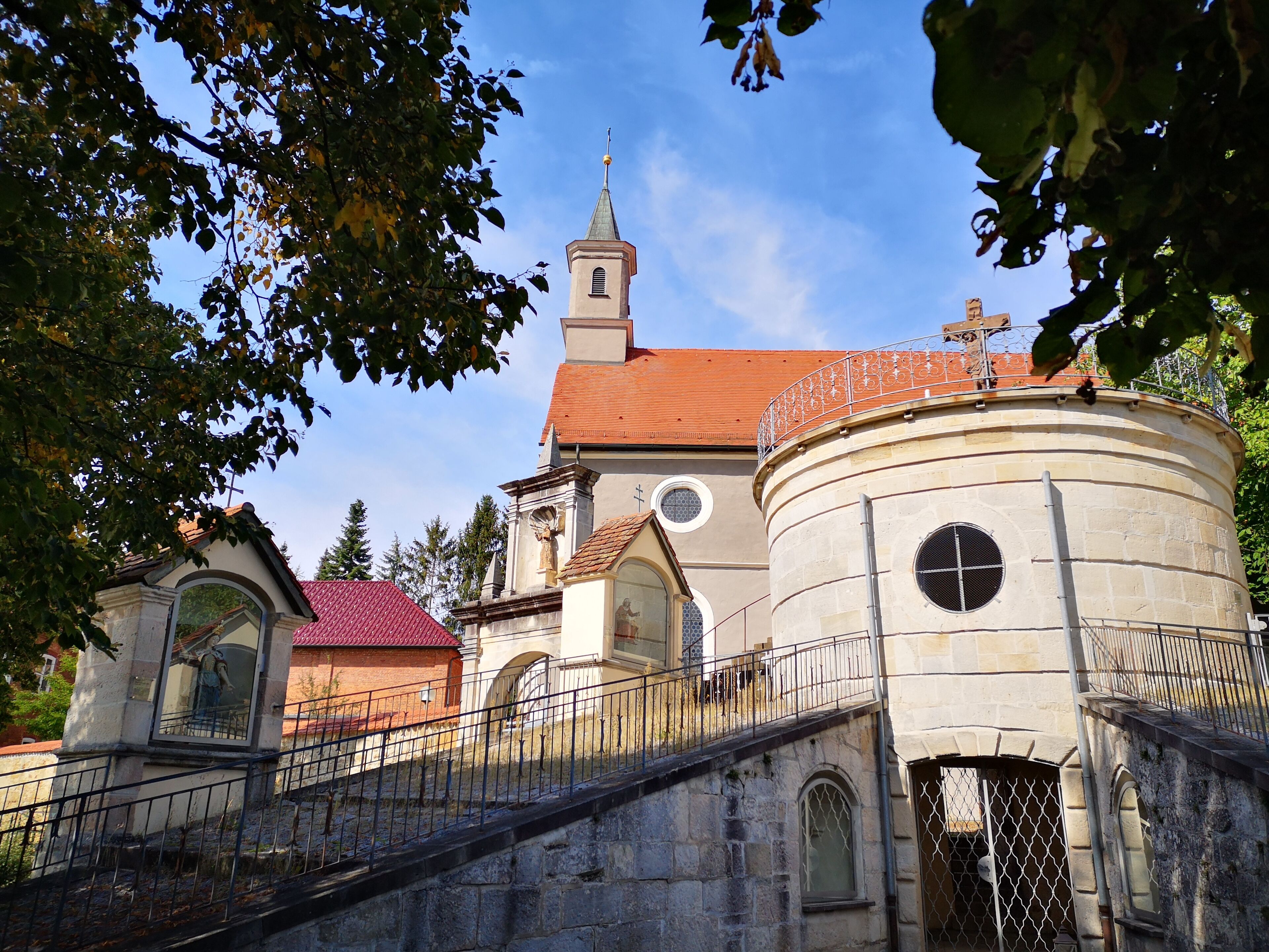 A church with a bell tower and a round building with a circular window.