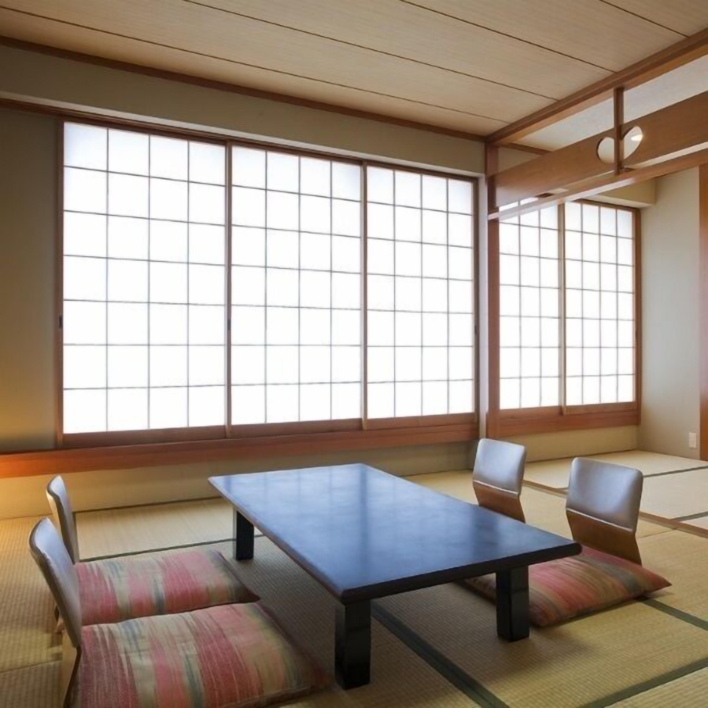 Een traditionele Japanse kamer met tatami vloerbedekking, een lage tafel en kussens.