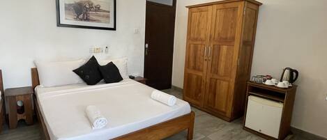 A bedroom with a wooden bed, a wardrobe, a small cabinet, and a framed picture on the wall.