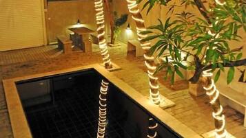 A swimming pool with decorative lights, palm trees, and potted plants.