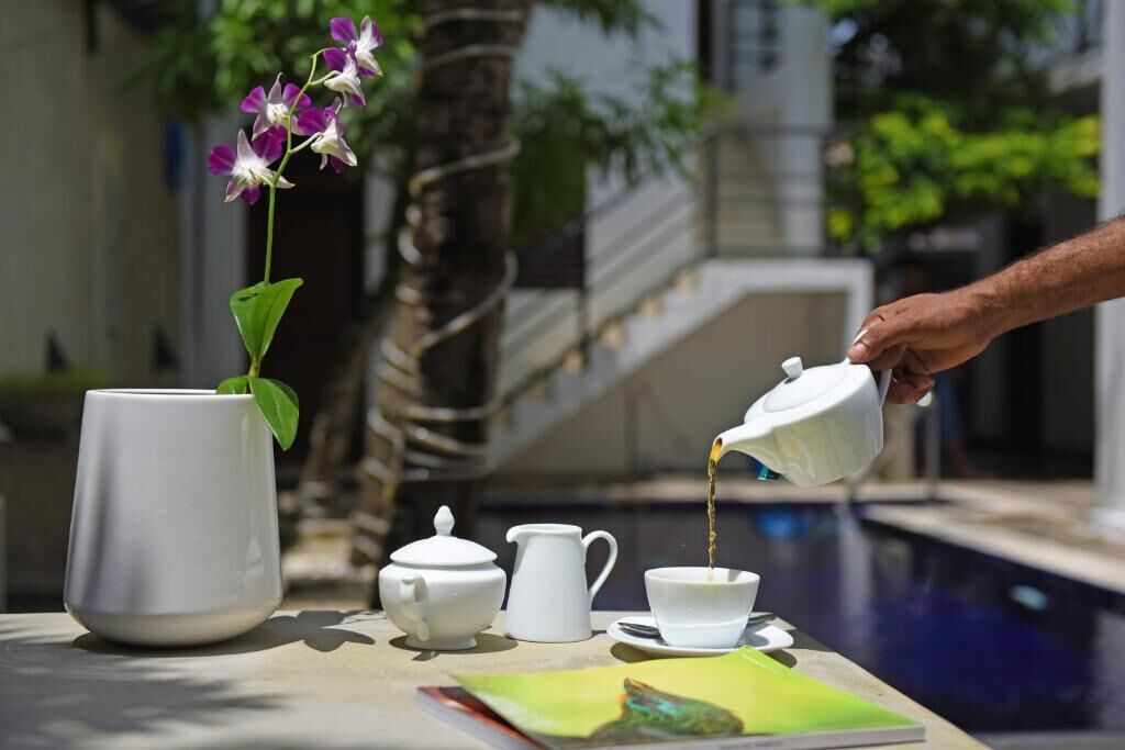 A table with a teapot, cup, pitcher, and a potted orchid.