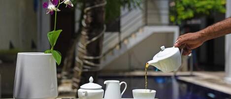 A table with a teapot, cup, pitcher, and a potted orchid.