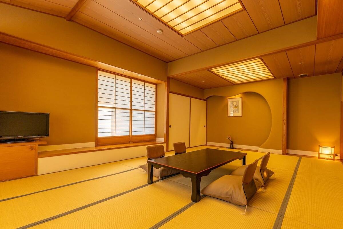 A traditional tatami room with a tatami mat floor, a low table, and sliding doors.