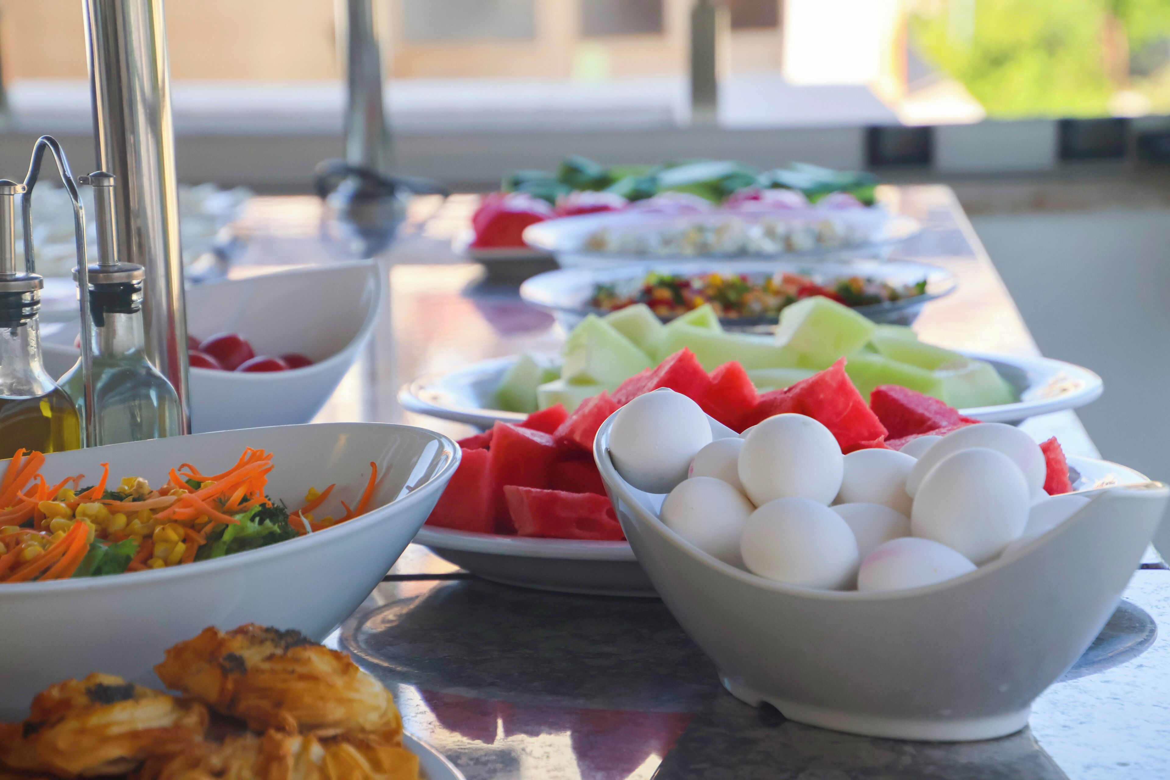 A table with various food items including salads, fruits, and eggs.