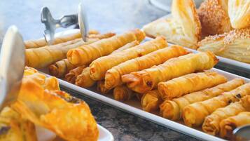 Buffet com rolinhos primavera, pão e uma colher.