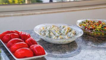 Een buffet met diverse gerechten, waaronder een salade met kikkererwten en een schotel met gesneden tomaten.