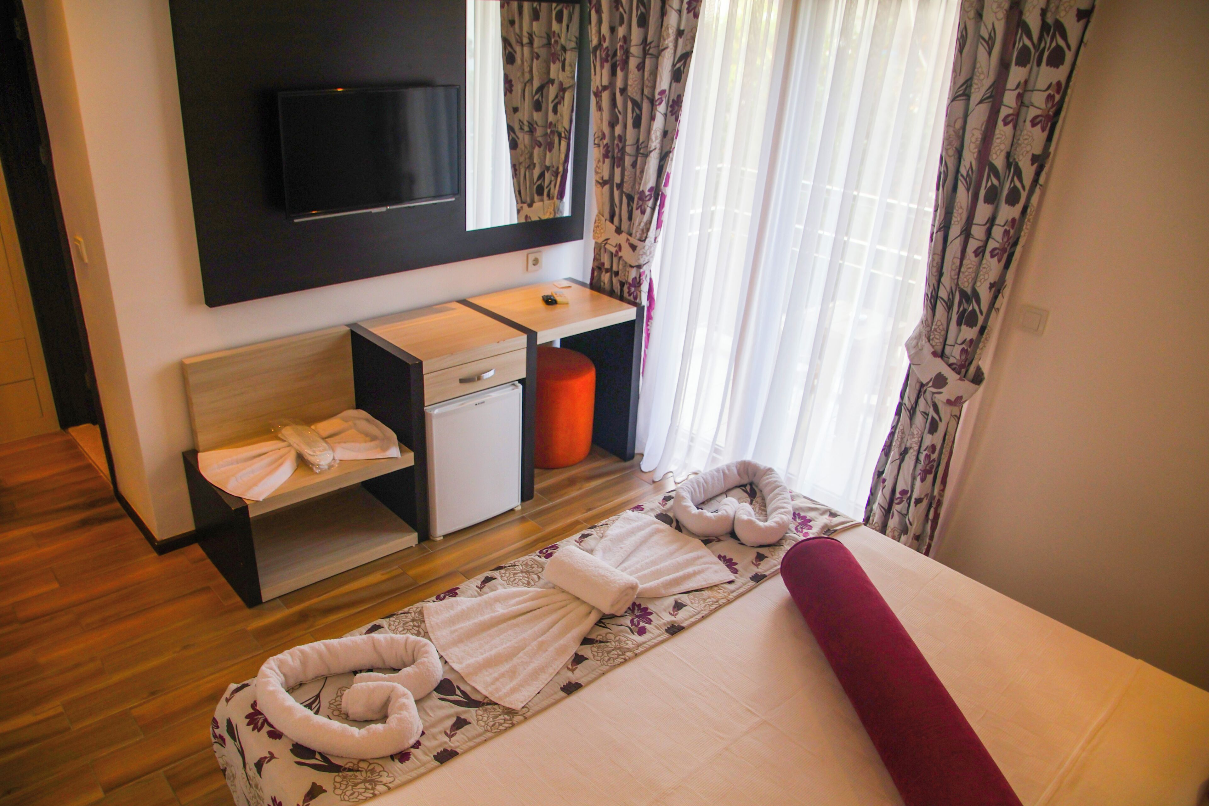 A hotel room with a bed, a desk, a television, and a bathroom.