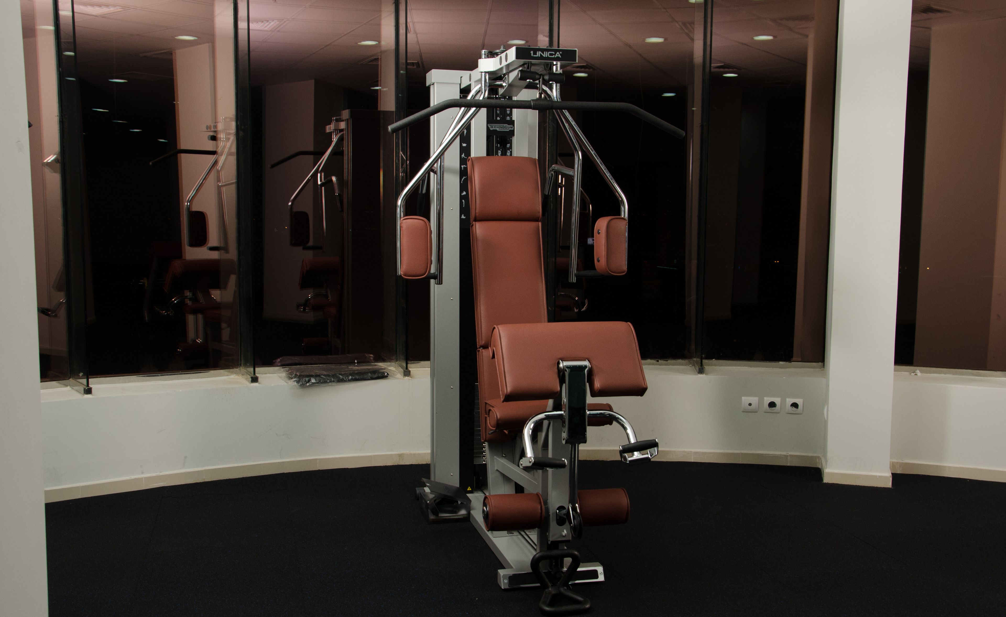 A gym with a bench press, a squat rack, and a mirror wall.