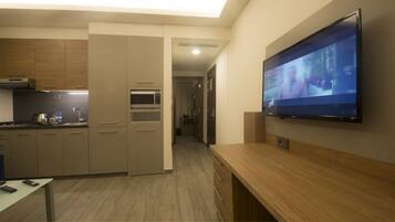 Una cocina moderna con microondas integrado, cafetera y televisor de pantalla plana en la pared.
