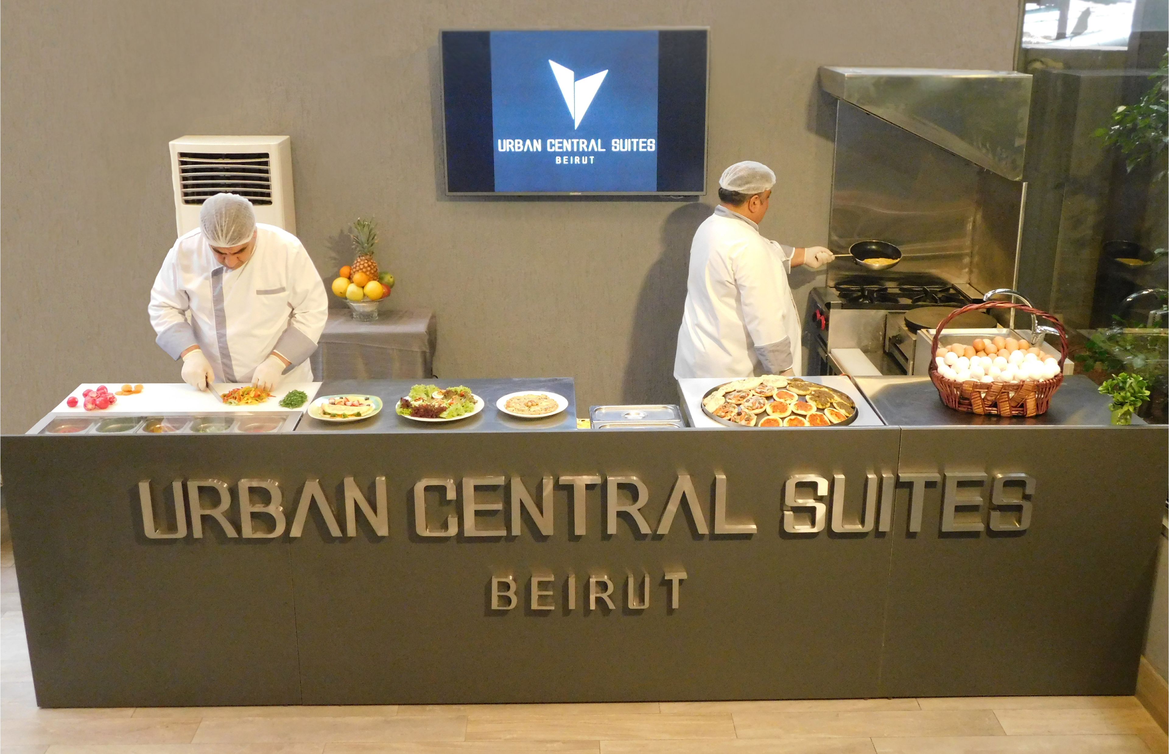 A buffet setup at Urban Central Suites in Beirut with chefs preparing food.