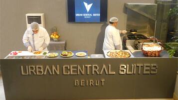 A buffet setup at Urban Central Suites in Beirut with chefs preparing food.