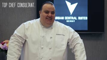 A chef standing behind a counter with various desserts.