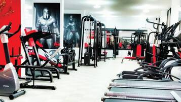 Un gimnasio con varios equipos de ejercicio, incluyendo cintas de correr, máquinas de pesas y una estructura para sentadillas.