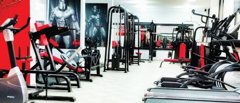 Una palestra con diverse attrezzature per esercizi, tra cui tapis roulant, macchinari per pesi e una panca per squat.
