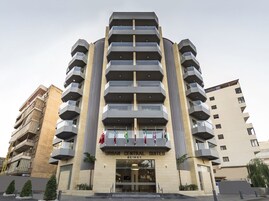 Un hotel moderno con varios pisos, balcones y una entrada destacada.