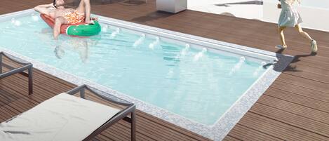 Relax by the rooftop pool with a stunning city view, surrounded by comfortable lounge chairs and lush greenery.
