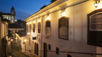 A narrow cobblestone street lined with historic buildings, featuring arched windows and traditional lighting fixtures.