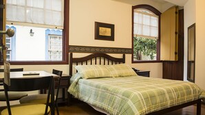 A bedroom with a bed, a desk, a chair, and a window with a view of a building. - Hotel Colonial (Ouro Preto)