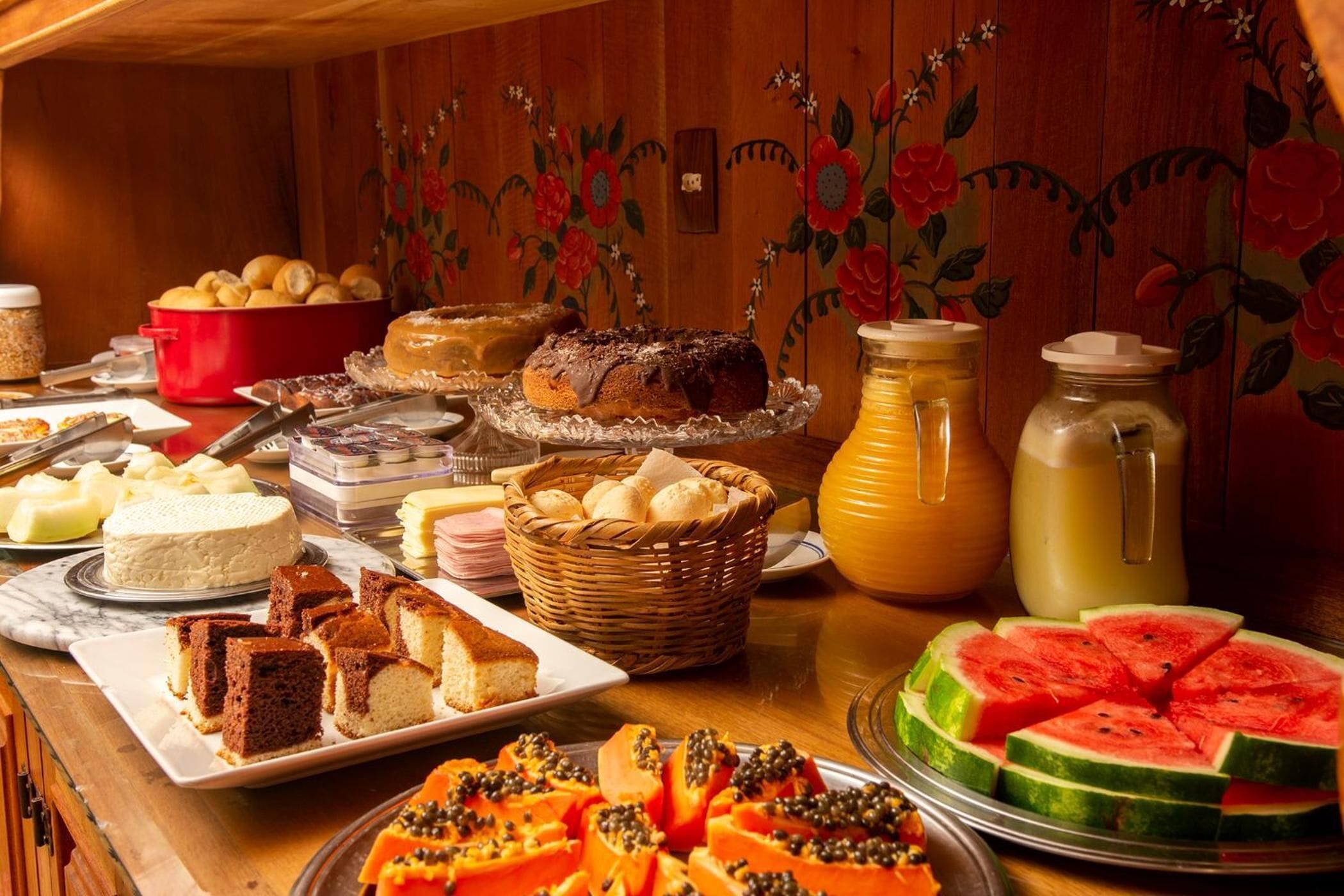 A buffet with various food items including cakes, bread, and fruits.