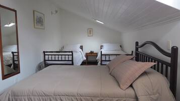 A single bed with a wooden headboard, a bedside table with a lamp, and a small bedside table with a phone.