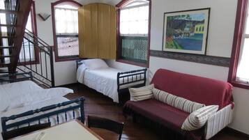 Una habitación con una cama litera, un sofá, una mesa de comedor y una escalera.