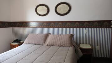 A hotel room with a bed, two bedside tables, a telephone, and two framed pictures on the wall.