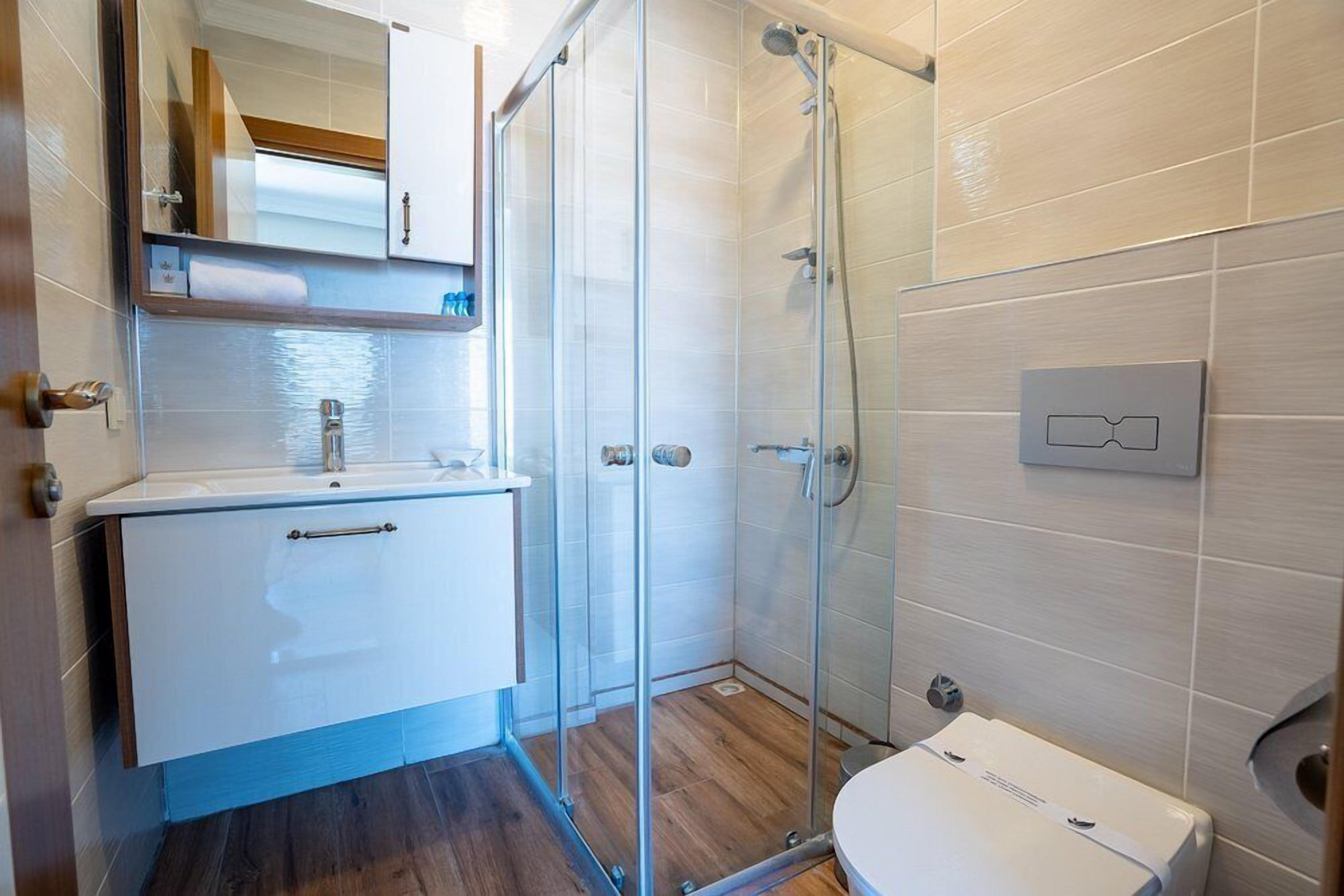 Une salle de bain avec une douche à parois de verre, un lavabo blanc et des toilettes.