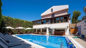 A modern hotel with a swimming pool, lounge chairs, and outdoor seating. - Cunda Giritlioğlu Otel (Ayvalik)
