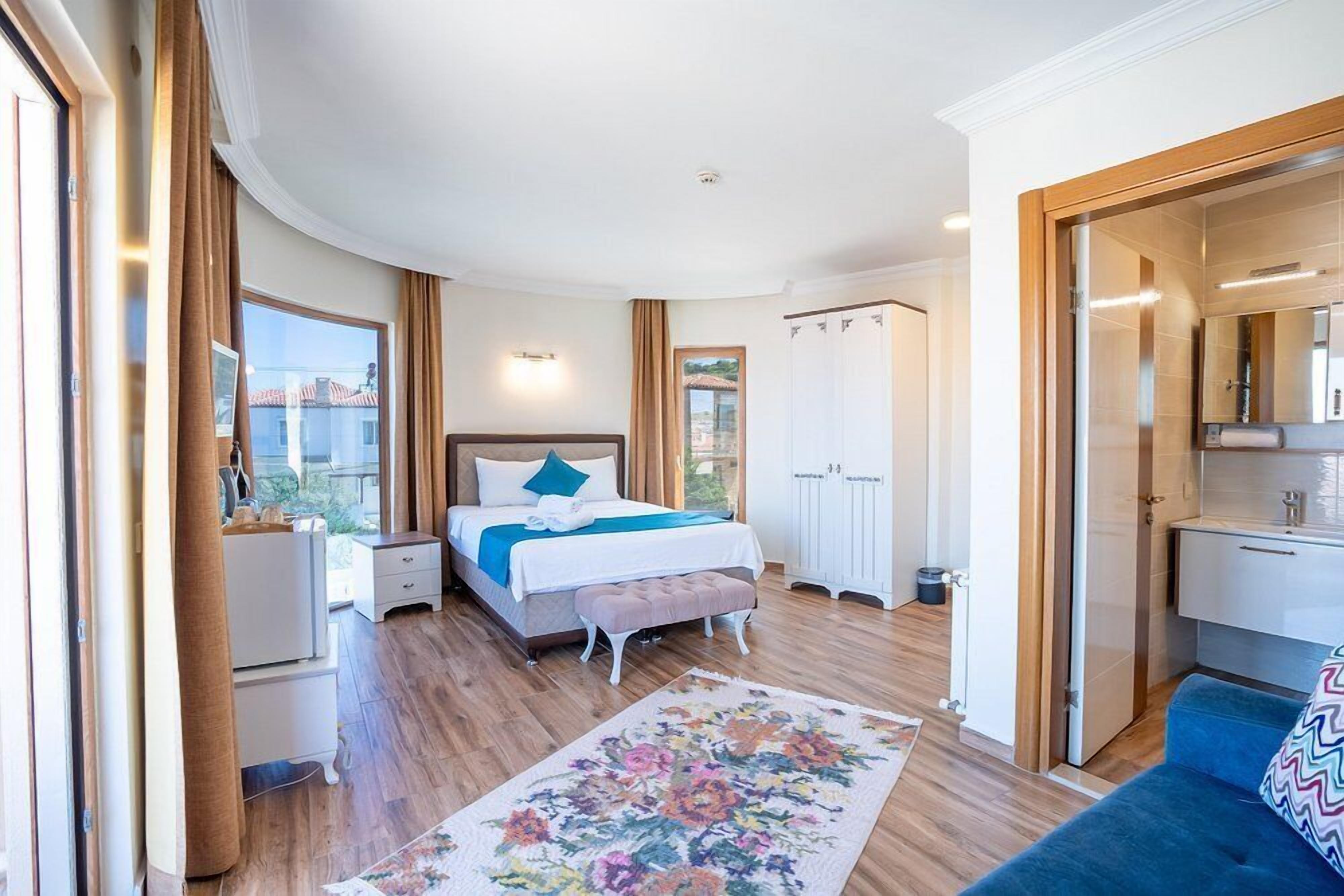 Un dormitorio con cama, mesitas de noche, cómoda, ventana y baño con ducha y lavabo.
