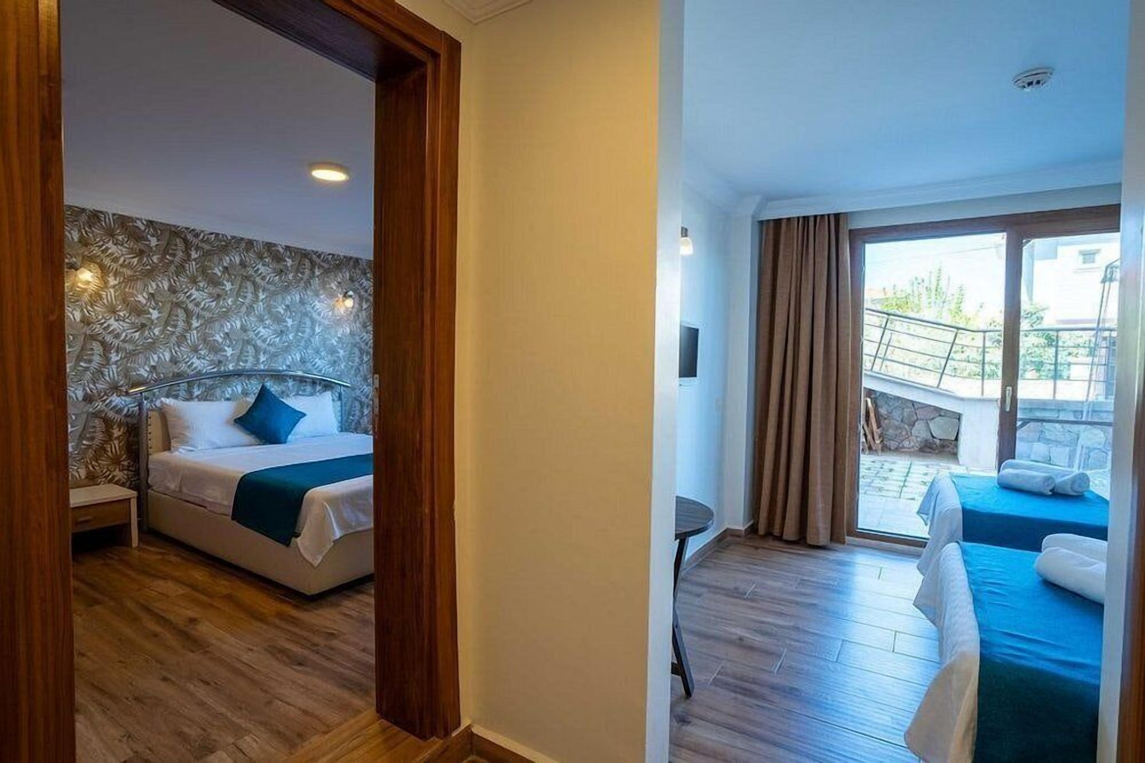 A hotel room with a bed, a small table, and a view of the outside.
