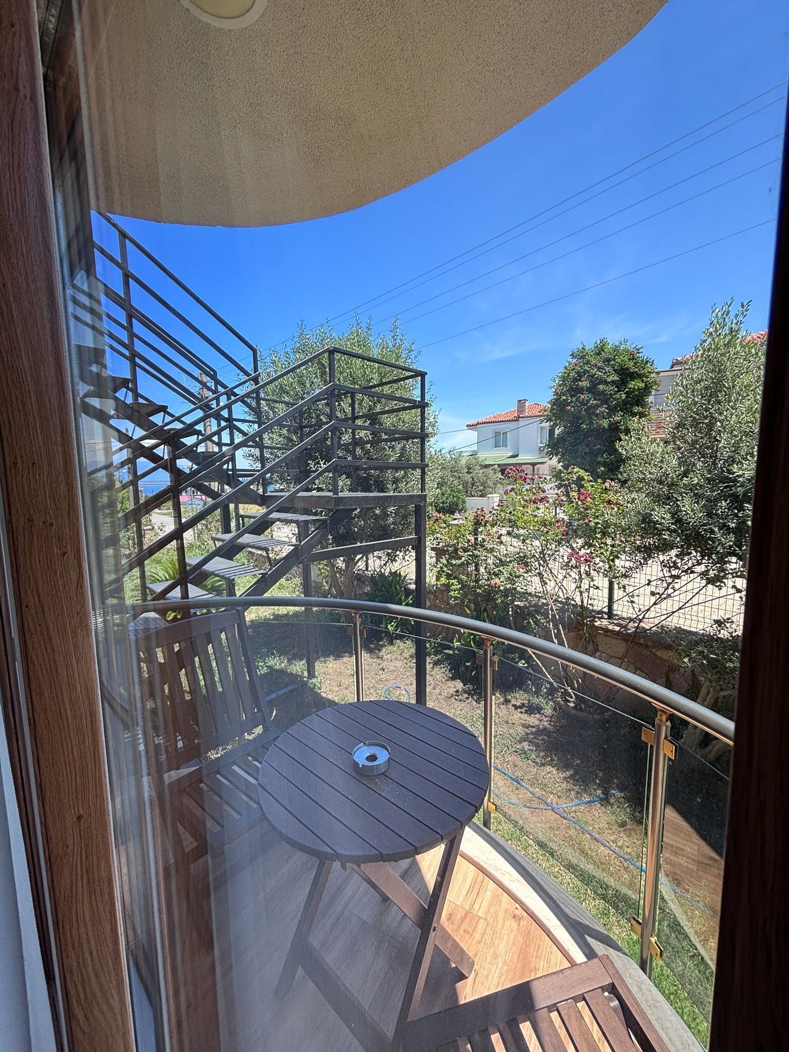 A balcony with a metal railing, a wooden table, and a spiral staircase.